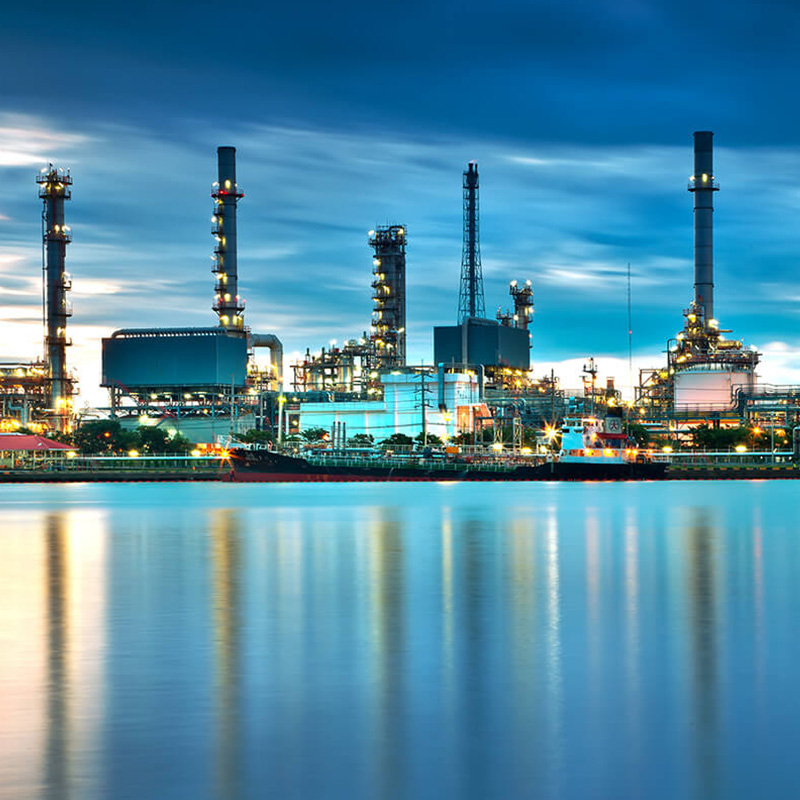 a large oil refinery sits next to a body of water.