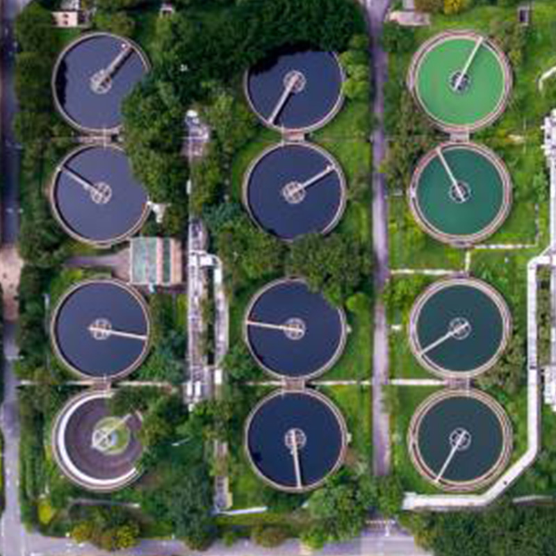 an aerial view of a water treatment plant surrounded by lush trees and grass.