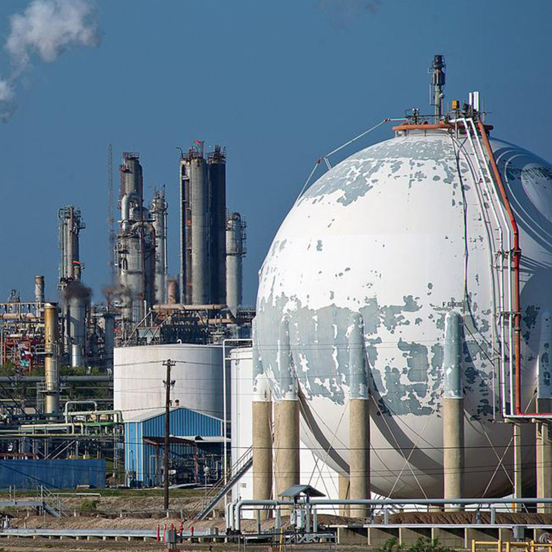 an oil refinery with a large spherical tank in the foreground.