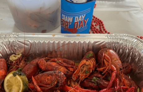 a container of crawfish sits in a tin foil pan that sites on a table.