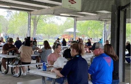 a group of people sitting at picnic tables under a pavilion.