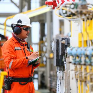 a man wearing a hard hat and headphones is writing on a clipboard.