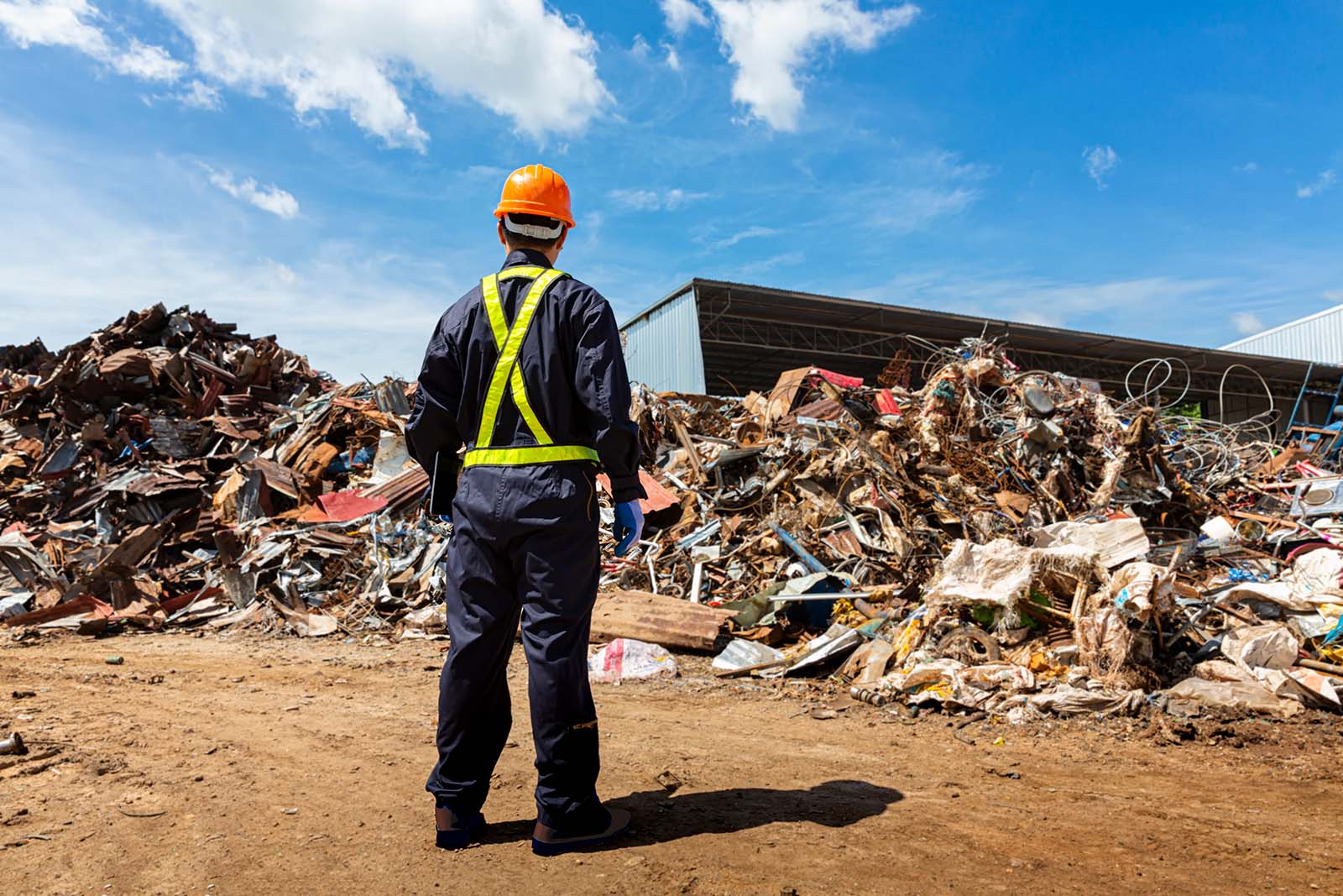 an engineer wearing a hard hat stands in front of a pile of trash.