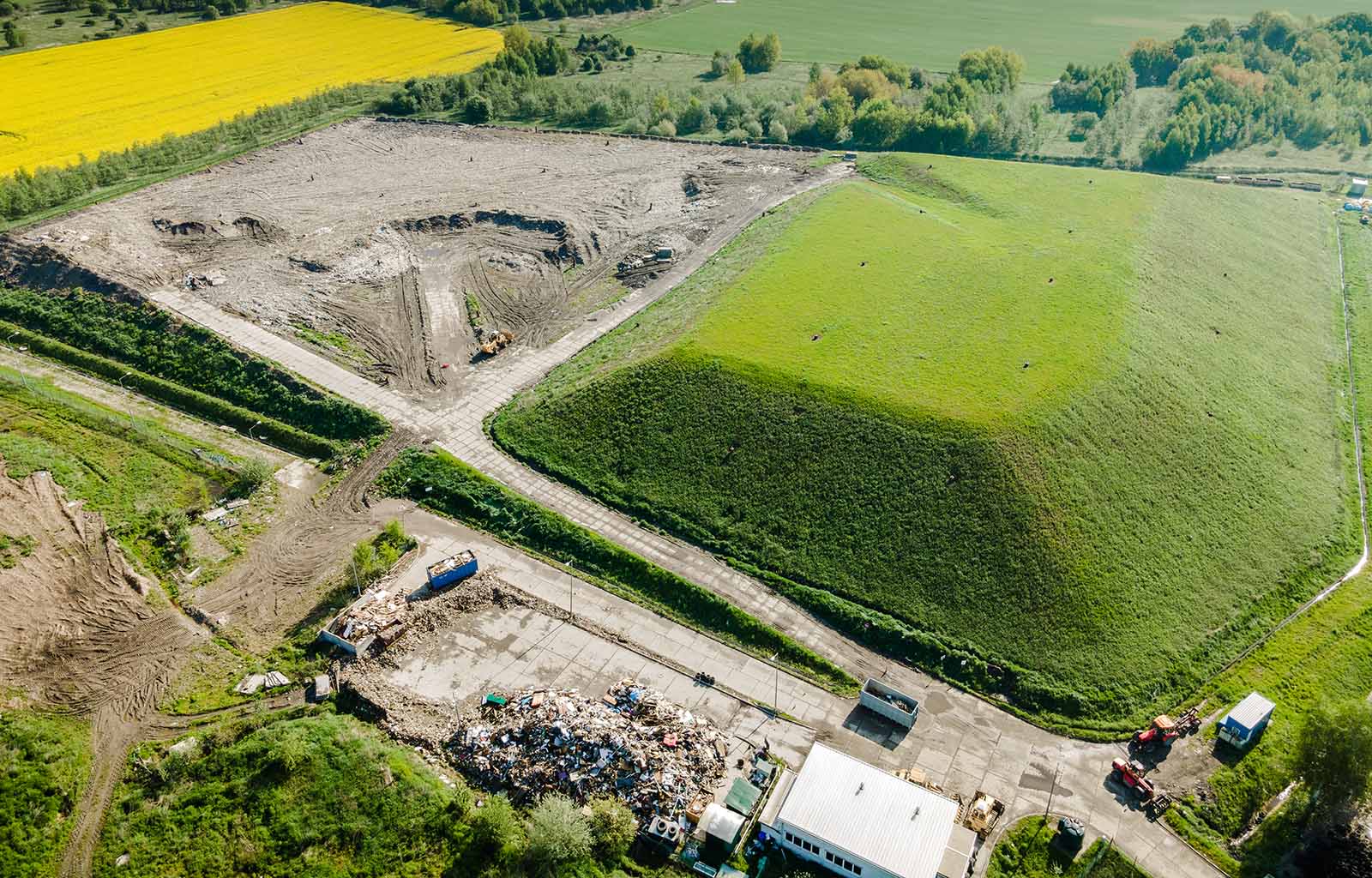 an aerial view of a landfill with a white building off to the side.