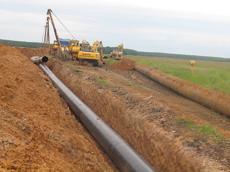 a yellow cranes working on a pipeline.