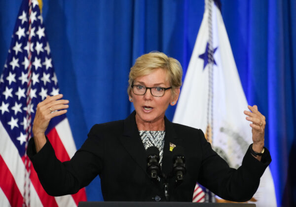 a woman stands at a podium with her arms outstretched.