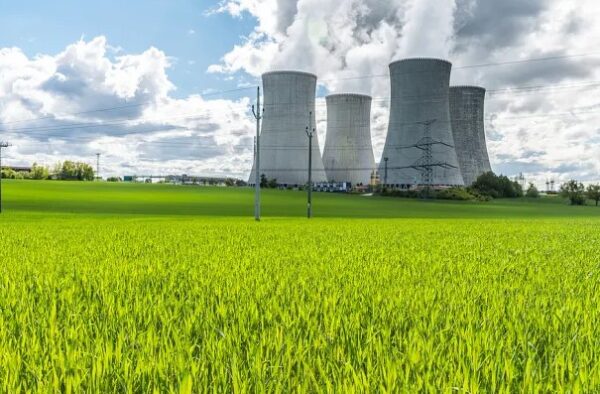 a nuclear power plant with cooling towers in the middle of a green field.