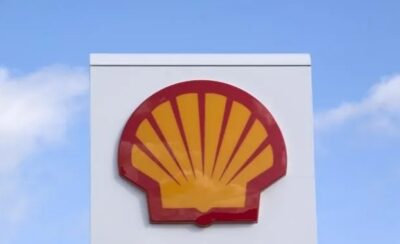 a Shell Gas logo on a white sign against a blue sky.